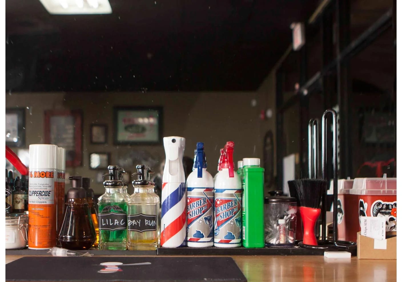 Counter lined with barber products including aftershave bottles, sprays, and brushes